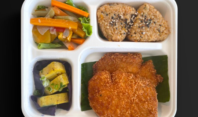 Obento japonés con cerdo empanizado (tonkatsu), onigiris, tamagoyaki y vegetales encurtidos